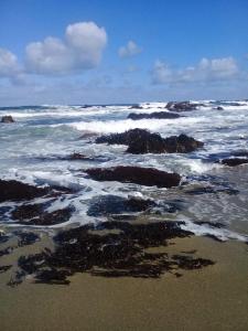 a beach with rocks in the ocean with waves at Hostería La Casa del Mar in Bahía Mansa