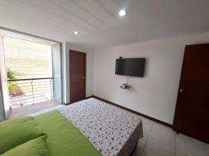 a bedroom with a bed and a flat screen tv at Apartamento Laureles la 33 in Medellín