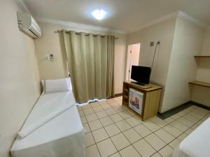 a room with two beds and a television in it at Villas diRoma com um dia no Acqua Park, Splash e Slide in Caldas Novas