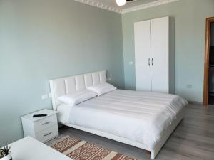 1 dormitorio con 1 cama blanca y armario blanco en Agroni Rooms, en Tirana
