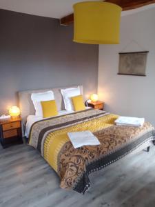Un dormitorio con una cama grande con almohadas amarillas y blancas en A deux pas du Rheby en Villebois