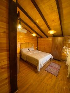 a bedroom with a bed in a wooden room at بلفيو كوخ in As Sayl aş Şaghīr