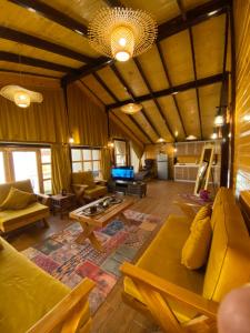 a living room with yellow couches and a table at بلفيو كوخ in As Sayl aş Şaghīr