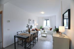 sala de estar con mesa, sillas y sofá en RentalSevilla Apartamento luminoso 2 dormitorios, en Sevilla