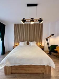 a bedroom with a large white bed with a chandelier at Rosco Apartment Transalpina in Alba Iulia