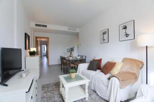 sala de estar con sofá blanco y TV en RentalSevilla Apartamento luminoso 2 dormitorios, en Sevilla
