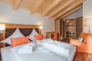 a bedroom with two beds and an orange chair at Chalets AurAlpin in Kleinarl
