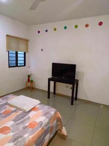 a bedroom with a bed and a desk with a television at Departamento en Altabrisa Merida in Mérida