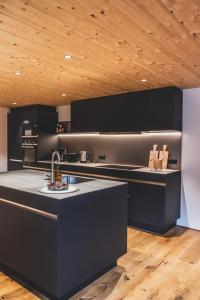 a kitchen with black cabinets and a counter top at Tante Anna Apartments in Sankt Gallenkirch