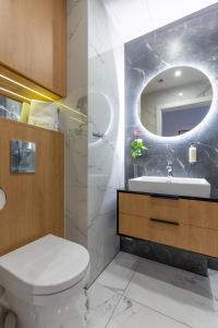 y baño con aseo, lavabo y espejo. en Apartments Kraków Rajska by Magnat, taras, winda, en Cracovia