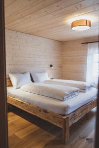 a large bed in a room with a wooden wall at Tante Anna Apartments in Sankt Gallenkirch