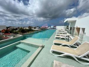 a row of lounge chairs next to a swimming pool at Anah Downtown luxury condo in Playa del Carmen