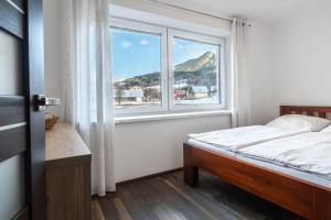 a bedroom with a bed and a large window at Apartmány Jánošík in Terchová