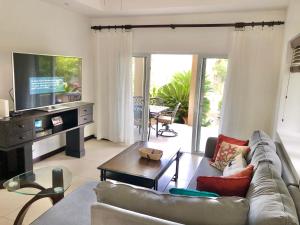 salon z kanapą i telewizorem w obiekcie Cosy 4bdr beach house in Ochio Rios w mieście Ocho Rios