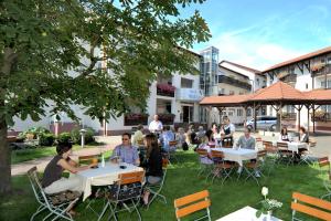 a group of people sitting at tables in a yard at Hotel Wolfringmühle in Fensterbach