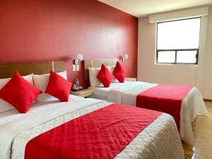 2 camas en una habitación de hotel con paredes rojas en Hotel Arbis, en Puebla