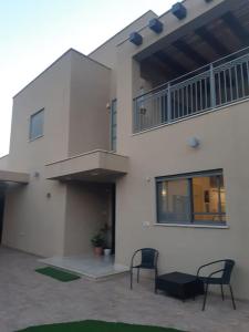 a white building with two chairs and a balcony at Adorable 3 bedroom Brenner "Hill" suite in Giv‘at Brenner