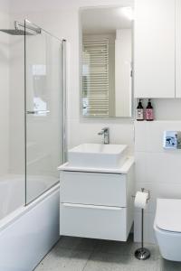 biała łazienka z umywalką i prysznicem w obiekcie Tree&Lake Apartament Warszawa w mieście Ząbki