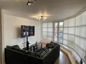 a living room with two couches and a flat screen tv at King Dems Home in Dagenham