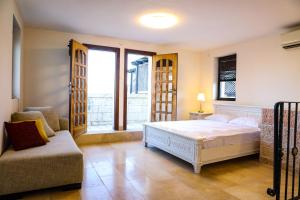 a bedroom with a bed and a couch and a window at The Maimon House- Old City, Jerusalem in Jerusalem