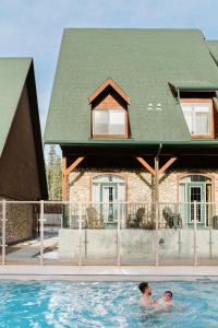 two people in a swimming pool in front of a house at Mount Rundle Hideaway with Heated Pool & Hot Tub and allows Pets in Canmore