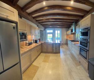 cocina grande con armarios blancos y techo de madera en La Bastide De Chassagne-Montrachet, en Chassagne-Montrachet