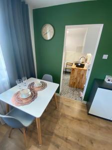una sala da pranzo con tavolo bianco e parete verde di Apartament Błogi Sen- komfortowy nocleg w sercu Bytomia a Bytom