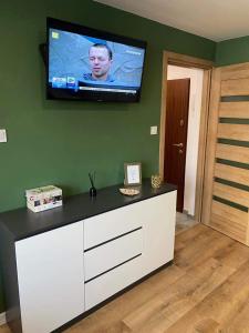 a living room with a tv on a green wall at Apartament Błogi Sen- komfortowy nocleg w sercu Bytomia in Bytom