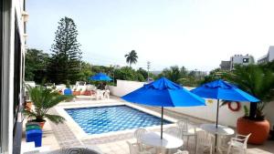basen ze stołami i niebieskimi parasolami obok w obiekcie Exclusivo apartamento Duplex Bahia fragata w mieście San Andrés