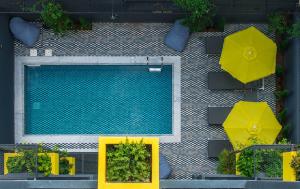an overhead view of a swimming pool with yellow tables and umbrellas at 3 Pines Design Living in Heraklio