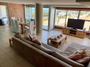 ein Wohnzimmer mit einem Sofa und einem Flachbild-TV in der Unterkunft Spacious 2 bedroom space with breathtaking seaview in Mossel Bay