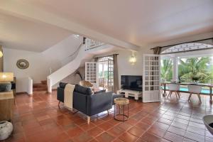 sala de estar con sofá y TV en Villa Caluma, magnifique villa de 3 chambres avec piscine et vue mer, accès rapide au golf, Trois ilets, en Les Trois-Îlets