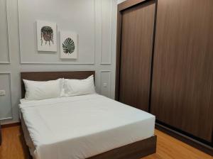 1 dormitorio con cama blanca y armario de madera en New 2BR Georgetown Warm and Lovely Homestay 10pax-无敌美景两房民宿 Beacon Executive Suite, en George Town