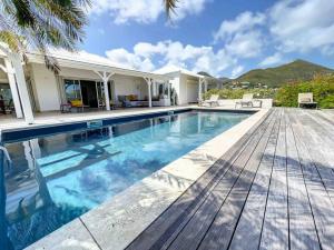 a swimming pool in a house with a wooden deck at Villa la Folie Douce, luxury and serenity, Orient Bay in Orient Bay
