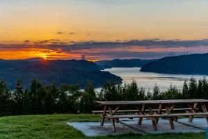 a picnic table in front of a lake at sunset at MontFJORD - Chalets, vue spectaculaire et SPA. ChantaFJORD #4 in Sacré-Coeur-Saguenay