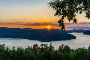 zachód słońca nad jeziorem z zachodem słońca w tle w obiekcie MontFJORD - Chalets, vue spectaculaire et SPA. ChantaFJORD #4 w mieście Sacré-Coeur-Saguenay