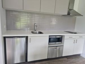 a white kitchen with a sink and a microwave at Moonah Links - Apartment 43 in Fingal