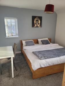 1 dormitorio con 2 camas, mesa y una foto en NO 7 Decent Home (Generous luxury bedroom) en Ashton under Lyne