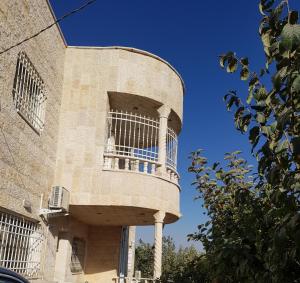 un edificio con balcone sul lato di Ibbin hospitality house a Ajloun