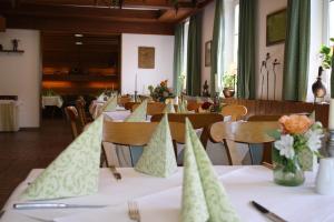 un comedor con mesas, sillas y flores en Dorfgasthof "Zur Rose", en Obereisenheim