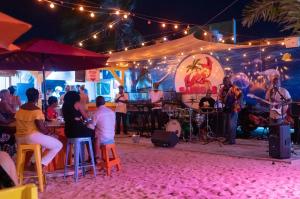 un grupo de personas sentadas alrededor de un escenario con una banda en Maho Beach Escape Luxe Studio Condo next to The Morgan Village, en Maho Reef