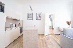 cocina y sala de estar con armarios blancos y suelo de madera en Bright Apartment in Old Town by Prague Days en Praga