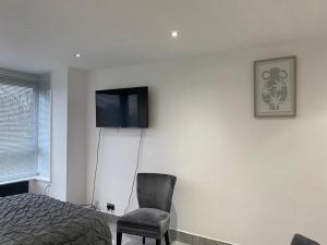 a bedroom with a bed and a chair and a television at Luxurious 2-Bed Apartment in Woolwich London in London