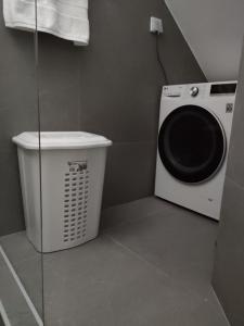 a laundry room with a washing machine and a trash can at Όμορφη οικία στο κέντρο της Σαλαμίνας. in Salamina