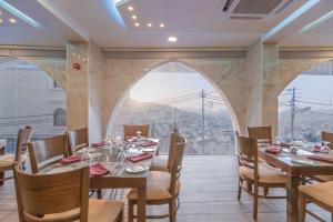 un comedor con mesas y sillas y una gran ventana en Petra Elite Hotel en Wadi Musa