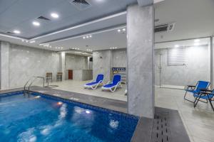 uma piscina com cadeiras azuis num quarto em Petra Elite Hotel em Wadi Musa