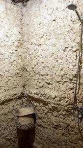 a stone wall with a shower and a basket at Muhra in Siwa