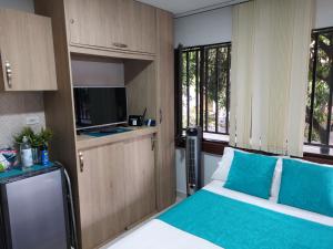 1 dormitorio con 1 cama con almohadas azules y TV en Apartaestudio Laureles - Viva Laureles, en Medellín
