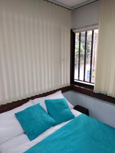 Un dormitorio con una cama con almohadas azules y una ventana en Apartaestudio Laureles - Viva Laureles, en Medellín