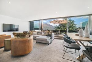 Una sala de estar con un sofá, una mesa y sillas. en Luxury Penthouse P2, en Queenstown
